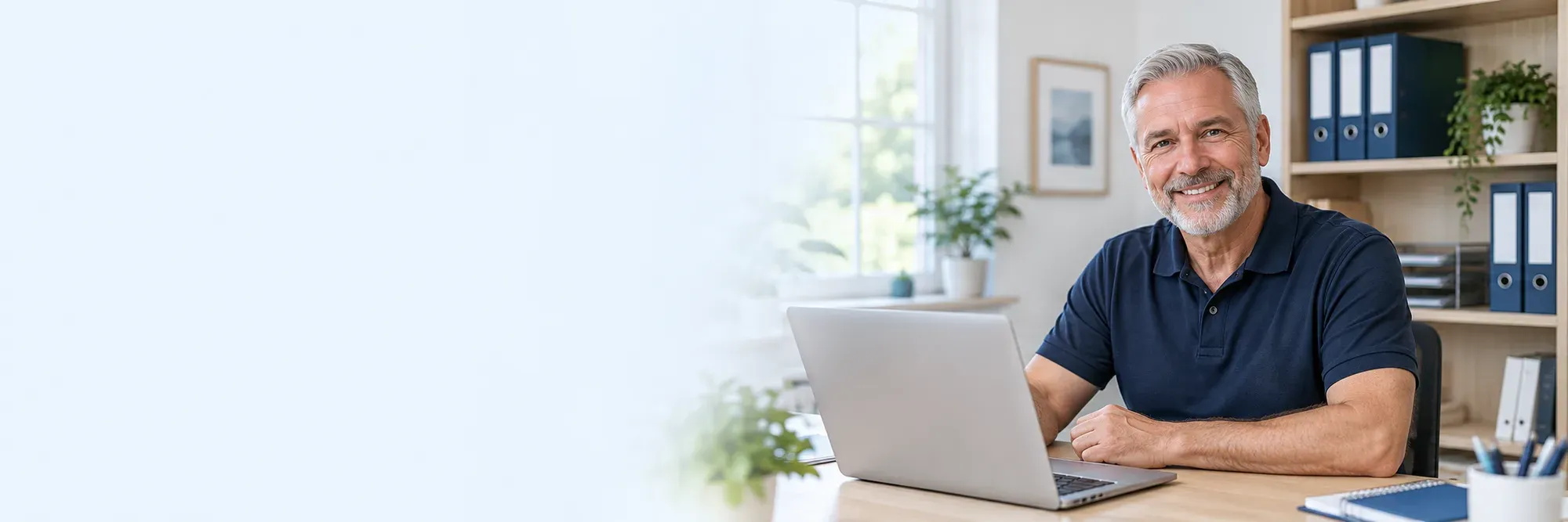 A friendly bookkeeper smiling at his desk with a laptop